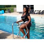 Olakemi - A curvy plus size model emerging from a pool wearing a black t-shirt and a plus swimsuit bottom