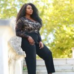 Olakemi - A curvy plus size model wearing a plus size black lace top and black pants by @fashionbookuk