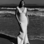 Plus size model Jessica Earle modeling a plus size white dress on the beach